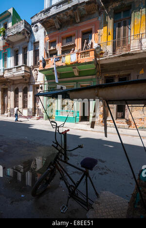 Bicycle taxi parked among crumbling buildings in a Central Havana neighborhood Stock Photo