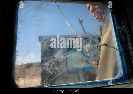 A Kurdish fighter of the People's Defense Forces HPG the military wing of the Kurdistan Workers' Party PKK is seen through a window of an armored vehicle which is riddled with bullet holes after a battle with ISIS or ISIL militants near the city of Kirkuk in northern Iraq Stock Photo