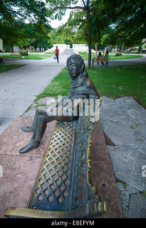 A bronze statue of Beatle John Lennon sitting on a bench in John Lennon park (formerly known as Parque Menocal) in Havana Cuba Stock Photo