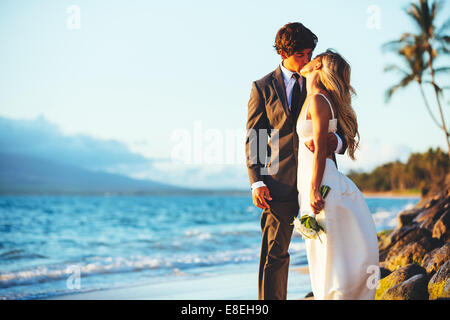 Romantic Wedding Couple Kissing on the Beach at Sunset Stock Photo