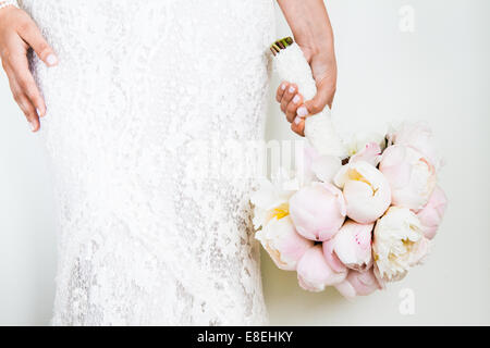 Woman Holding a nice Wedding Bouquet in front of a white Wall Stock Photo
