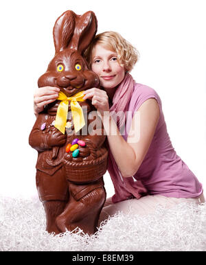 Blond Girl Adjusting Bowtie of a Chocolate Easter Bunny Isolated on White Background Stock Photo