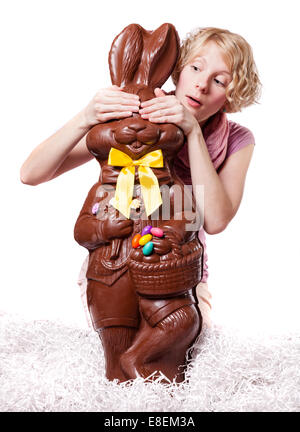 Blond Girl Hiding the eyes of a Chocolate Bunny Isolated on white background Stock Photo