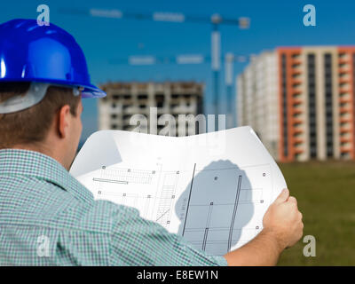 back view, closeup of male caucasian engineer at work looking at technical drawing plan Stock Photo