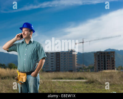 portrait of caucasian engineer talking on phone on residential construction site Stock Photo