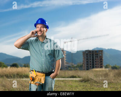 portrait of caucasian smiling engineer talking on phone on residential construction site Stock Photo