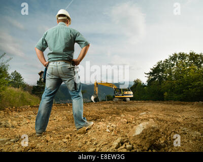 back view of male engineer standing on construction site evaluating the progress Stock Photo
