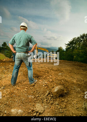 back view of male engineer standing on construction site evaluating the progress Stock Photo