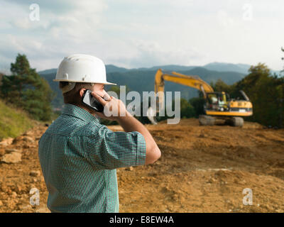 male engineer talking on the phone while supervising construction Stock Photo