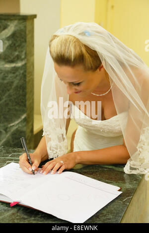 Bride signing the church register after the ceremony Stock Photo
