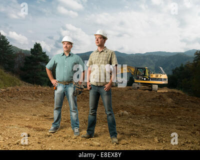 two young caucasian engineers standing on construction site outdoors Stock Photo