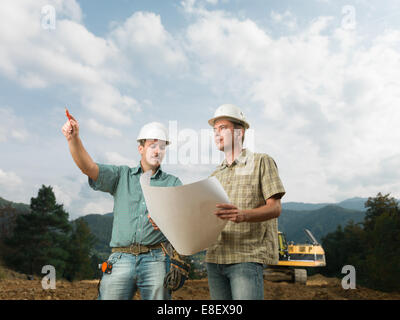 two handsome caucasian engineers comparing blueprint with actual construction Stock Photo