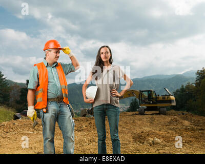 male and female engineers standing on construction site outdoors Stock Photo