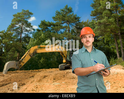 caucasian male architect taking notes on clipboard at construction site Stock Photo