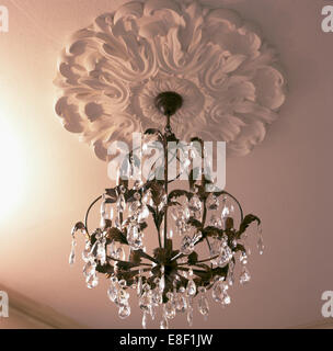 Close-up of glass chandelier hanging from ornate plaster ceiling rose Stock Photo