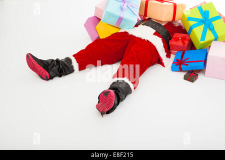 santa claus too tired to lie on floor with many gift boxes over white background Stock Photo