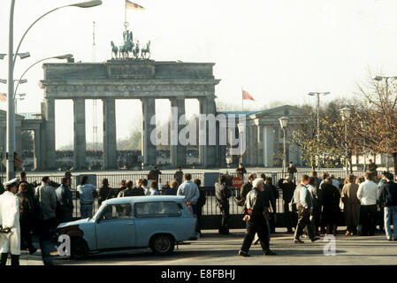 One day after the opening of the Wall, curious onlookers stand at the border fence in front of Brandenburg Gate on the eastern side of Berlin, 10 November 1989. Several hundreds of people already sit on the Wall behind the Gate. From West Berlin, they climbed the western side of the Wall which is several metres thick in this location. Brandenburg Gate was opened as a border crossing as late as 22 December 1989. Photo: Michael Richter Stock Photo
