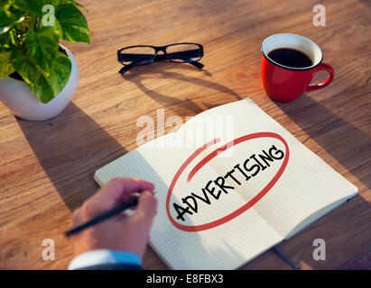 Hand with a Note and a Single Word Advertising Stock Photo