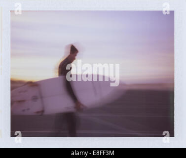 Blurred motion shot of a man carrying a surfboard, California, USA Stock Photo