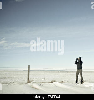 woman looking through binoculars in winter, Wyoming, United States Stock Photo