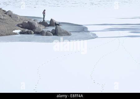 Woman with dog standing by  frozen lake, Colorado, United States Stock Photo
