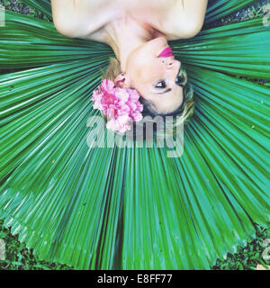 Australia, Woman lying on palm leaf Stock Photo