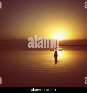 Silhouette of a Man standing in the Dead Sea at sunset, Israel Stock Photo