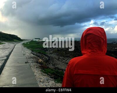 Man in rain jacket by coast Stock Photo