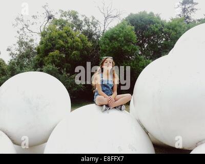 Girl sitting on a sculpture in a park, Australia Stock Photo