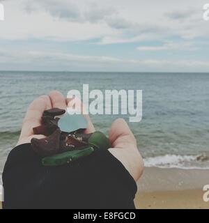 Woman's hand holding pebbles on beach Stock Photo