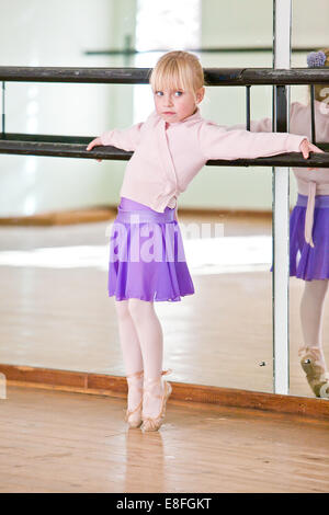 Girl leaning against barre in ballet studio Stock Photo