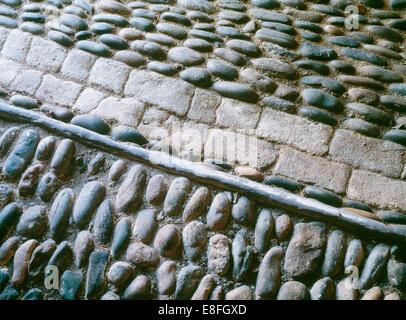 Detail of cowshed floor with cobblestones, brick drain & slate edging in Carreg Fawr Victorian farmyard, Bardsey Island, Wales. Stock Photo