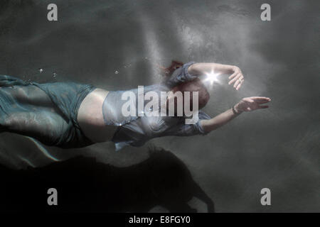 Fully clothed Pregnant woman swimming underwater Stock Photo