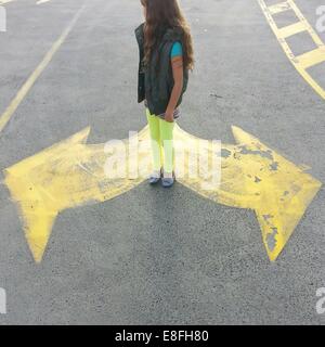 Girl standing on road between arrow road markings, Australia Stock Photo
