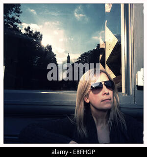 Portrait of a woman sitting in front of a window in the sun Stock Photo