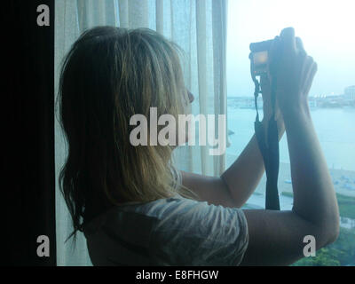 Woman taking photograph out of a window