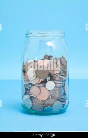 Close-up of a glass jar three quarters full of assorted UK coins Stock Photo