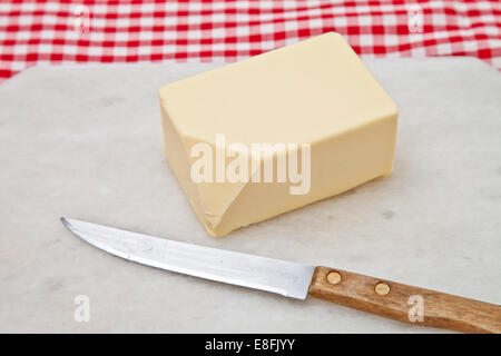 Close-up of a block of butter and knife on a chopping board and checked napkin Stock Photo