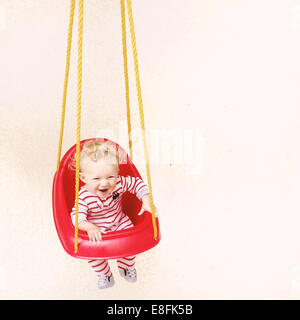Happy Baby Boy in pyjamas sitting in a swing