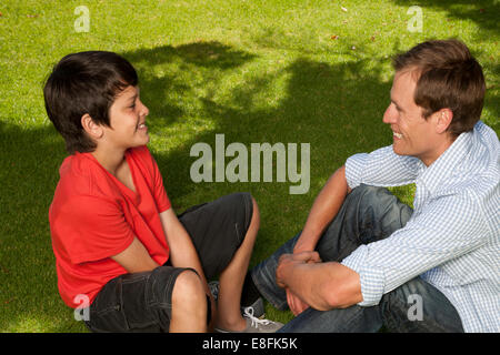 Father sitting in garden talking to his son, Cape Town, Western Cape, South Africa Stock Photo