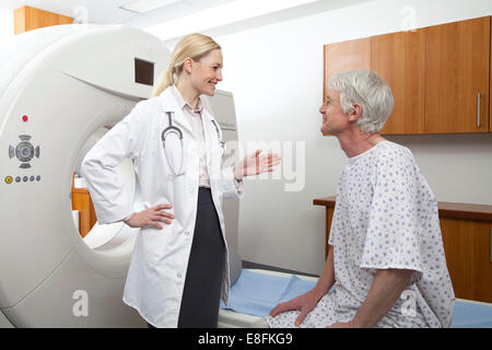 Female doctor talking to a male patient in hospital scanning room Stock Photo