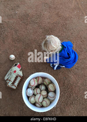 Boy collecting baseball balls in a ball bucket, California, USA Stock Photo