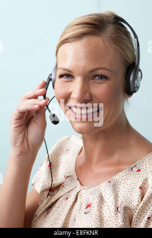 Smiling woman talking on the phone using a telephone headset Stock Photo