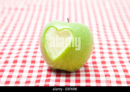 Heart Shape missing From the Side Of a Green Apple on a checked tablecloth Stock Photo