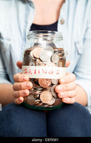 Woman holding a jar with coins Stock Photo