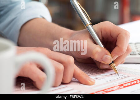 Close up of woman signing a document Stock Photo