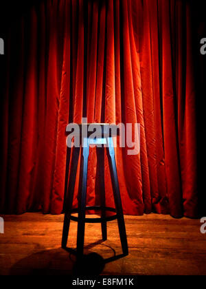 Stool on a stage in front of red curtain Stock Photo