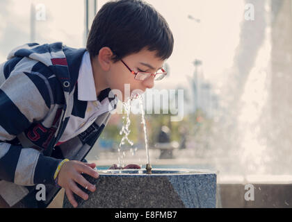 Spain, Cordoba, Boy (12-13) drinking water from fountain in park Stock Photo