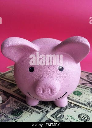 Close-up of pink piggy bank with dollar bills Stock Photo