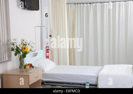 Empty hospital bed on hospital ward with flowers Stock Photo